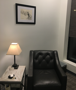 Comfortable chair in office next to soft light of lamp.